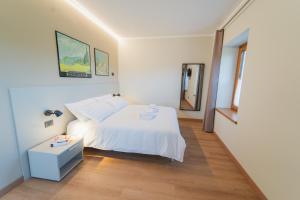a white bedroom with a bed and a table at Corte Bonfiglio Colombari in Illasi +40 photos