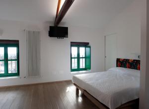 ein weißes Schlafzimmer mit einem Bett und zwei Fenstern in der Unterkunft Da Cuful in Reana del Roiale