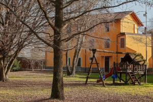 ein Spielplatz in einem Park mit einem Baum und einer Schaukel in der Unterkunft Da Cuful in Reana del Roiale