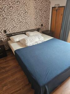a bedroom with a bed with blue sheets and a wall at Hostel Hostel in Batumi