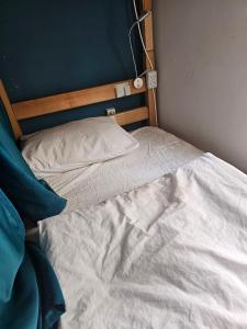 an unmade bed with white sheets and a blue wall at Hostel Hostel in Batumi