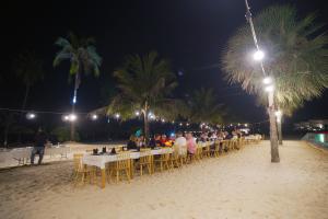 a group of people sitting at tables on the beach at night at The One Resort in Koh Rong Island +156 photos