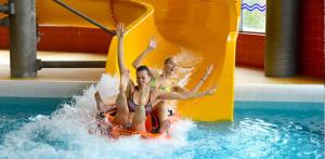 two girls riding on a water slide in a pool at Family hotel Maxim in Beroun
