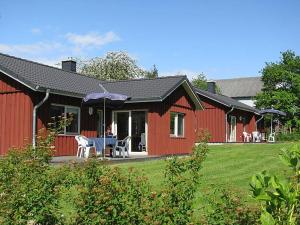 a woman sitting at a table outside of a red barn at Seeschwalbe in Munkbrarup