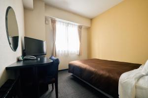 a hotel room with a bed and a desk with a mirror at Urbain Hiroshima Central in Hiroshima