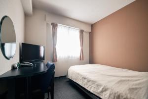 a bedroom with a bed and a desk with a mirror at Urbain Hiroshima Central in Hiroshima