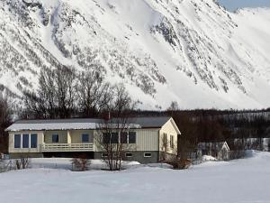 a house in the snow in front of a snow covered mountain at Northern Light Lodge - Lyngen in Veidal