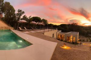 a house with a swimming pool with a sunset in the background at Villa Calella Brava in Calella de Palafrugell