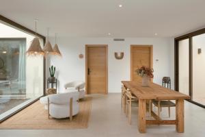 a dining room with a wooden table and white chairs at Villa Calella Brava in Calella de Palafrugell