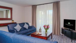 a living room with a blue couch and a tv at Castle Oaks House Hotel in Limerick