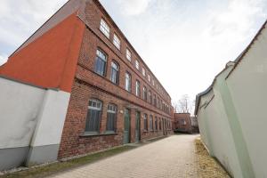 a red brick building with a cobblestone street next to it at Fabrik68 - ganzes Haus 3 Schlafzimmer 2 Bäder in Peitz