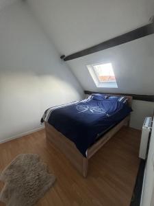 a bedroom with a bed with a blue comforter and a window at Maison in Verneuil-en-Halatte