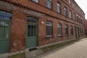 a brick building with green doors on a street at Fabrik68 - ganzes Haus 3 Schlafzimmer 2 Bäder in Peitz