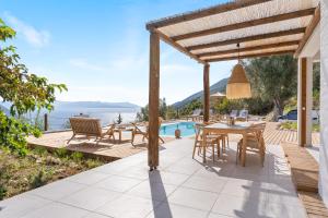 a patio with a table and chairs next to a pool at ELGIAN Luxury Villa -Private Pool & Sea View in Póndi