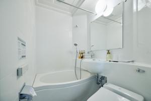 a white bathroom with a tub and a sink and a mirror at Urbain Hiroshima Central in Hiroshima +21 photos
