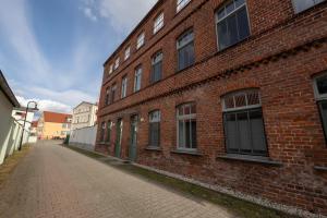a red brick building with windows on a street at Fabrik68 - ganzes Haus 3 Schlafzimmer 2 Bäder in Peitz