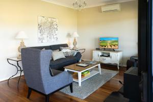 a living room with a blue couch and a tv at Red Door Collective - RDC Vineyard Estate, Luxury Adult Only Stay in Pokolbin
