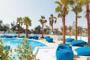 a pool with palm trees and blue pillows at W Dubai - Mina Seyahi in Dubai