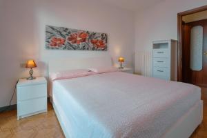 a white bedroom with a bed and a painting on the wall at House Carla in Bellano