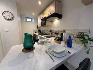 a kitchen with a table with plates and a clock at Le Cabrol Grand studio Hyper centre WIFI 2ème étage in Rodez