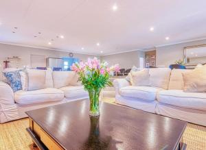 a living room with couches and a vase of flowers on a table at Riverside Rhapsody, Vaal River, Vanderbijlpark, 6 Adults and 4 Children in Vanderbijlpark