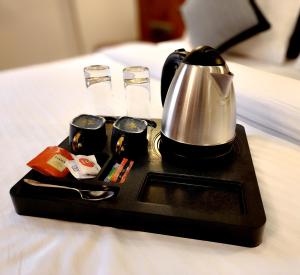 a tray with a tea kettle and cups on a bed at The Falcon Inn - Clare Road in Mumbai