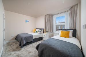 a bedroom with two beds and a window at Exquisite 4Bedroom House 4 Contractors & Large Families with Private Garden, Fully Equipped Kitchen and Close Proximity to Train & Bus Stations in Finchley
