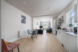 a kitchen and living room with a table and chairs at Exquisite 4Bedroom House 4 Contractors & Large Families with Private Garden, Fully Equipped Kitchen and Close Proximity to Train & Bus Stations in Finchley +18 photos