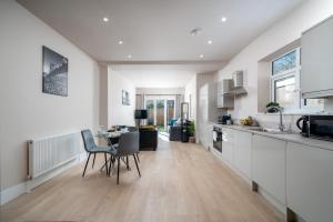 a kitchen and living room with a table and chairs at Exquisite 4Bedroom House 4 Contractors & Large Families with Private Garden, Fully Equipped Kitchen and Close Proximity to Train & Bus Stations in Finchley
