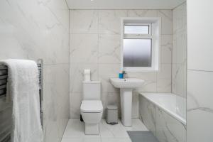 a white bathroom with a toilet and a sink at Exquisite 4Bedroom House 4 Contractors & Large Families with Private Garden, Fully Equipped Kitchen and Close Proximity to Train & Bus Stations in Finchley