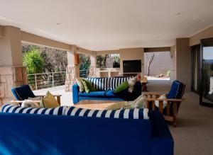 a living room with blue couches and chairs and a tv at Elements Private Golf Villa 295 in Warmbaths