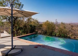 an umbrella sitting next to a swimming pool at Elements Private Golf Villa 295 in Warmbaths