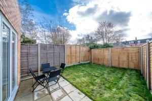 a backyard with a fence and a table and chairs at Exquisite 4Bedroom House 4 Contractors & Large Families with Private Garden, Fully Equipped Kitchen and Close Proximity to Train & Bus Stations in Finchley