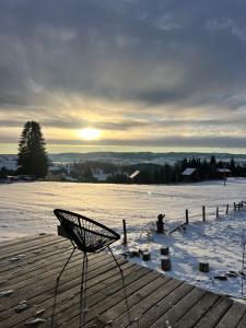 a bench sitting on a deck in the snow at Mokki - A-frame cozy în Apuseni in Mărişel