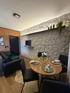 a living room with a table and a stone wall at Apartamento COMPLETO- Próximo ao shopping JL in Cascavel