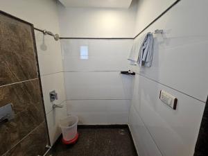 a bathroom with a shower and a towel on a wall at Hotel Mayur by RoomsInc Katra in Katra +30 photos