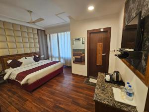 a hotel room with a bed and a television at Hotel Mayur by RoomsInc Katra in Katra