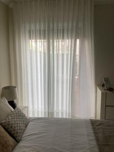 a bedroom with a large window with white curtains at Modern room (with deck) in Povoação