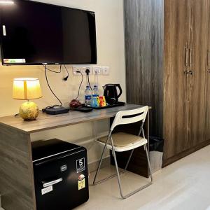 a desk with a television and a chair in a room at Hotel I Live Inn in Chennai