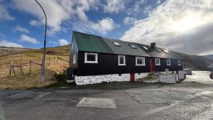 a black house with a green roof on a hill at Válur Cozy Cottage in Válur