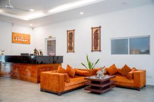a living room with two orange couches and a table at Lavendish Wild Safari in Wasgamuwa