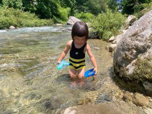 a young child playing in the water in a river at Family Homestay Shirokuro Guesthouse in Nakakiri +7 photos