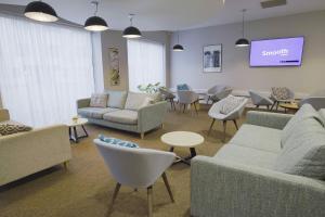 a waiting room with couches and chairs and a tv at Sunley Hotel in Northampton