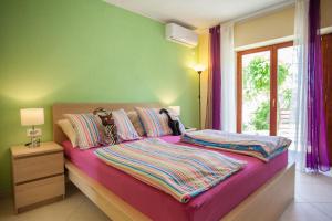 a bedroom with a bed with purple sheets and a window at Apartment Dunja in Cres