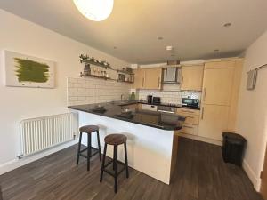 a kitchen with a counter and two bar stools at Spacious 2 Bed 2 Shower Apartment in Crewe