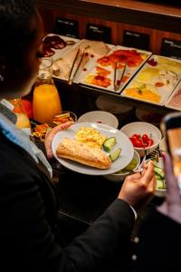 a person taking a picture of a table with a plate of food at Hôtel Paris Neuilly in Neuilly-sur-Seine +45 photos