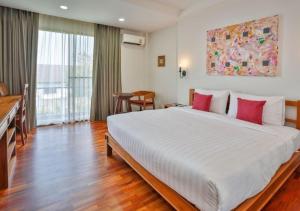 una camera da letto con un grande letto bianco con cuscini rossi di Sansuntree a Lamphun