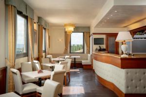 a restaurant with tables and chairs and windows at Hotel Athena in Siena