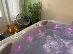 a bath tub with pink lights in a bathroom at The Originals Boutique, Hôtel Normandie, Auxerre in Auxerre