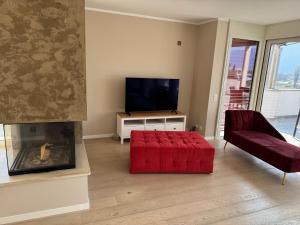 a living room with a red ottoman and a television at Rotonda in Gordola